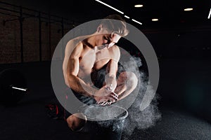 Fitness model trainer rubs his hands with chalk and talc so that fingers do not slip or slide.