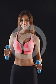 Fitness model woman with dumbbells at studio