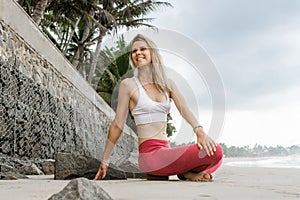 Fitness and motivation. Healthy athlete girl stretching on beach on sunny day. Fit woman doing yoga at seaside