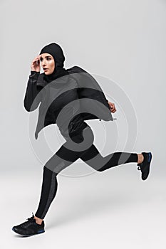 Fitness muslim woman posing running jumping isolated over white wall background