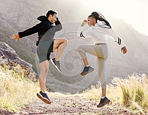 Fitness, nature and couple exercise in mountain hill, jump wellness and outdoor cardio workout on dust path. Motivation