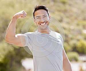 Fitness, nature and a man flexing biceps with a smile while training in outdoor park. Power, flex and stretch before