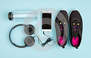 Fitness objects on blue background. Sneakers, water and audioplayer