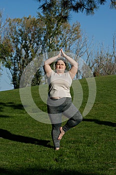 Fitness, outdoor training, weight loss. Fat woman doing exercises, yoga in nature. Healthy lifestyle
