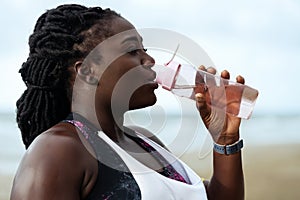 Fitness, people and healthy lifestyle- african woman drinking water after sport