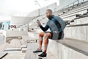 Fitness, phone and man thinking on stadium steps for training break, pause or social media scroll. Arena, stairs and