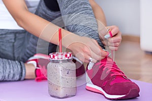 Fitness Prep: Young Attractive Female with Detox Smoothie and Red Sneakers on Purple Yoga Mat