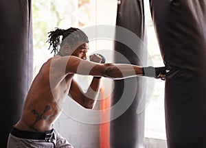 Fitness, punching bag and black man in gym for exercise, boxing challenge or competition training. Power, muscle and