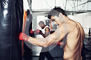 Fitness, punching bag and man with boxing gloves at a gym for training, resilience or performance. Sports, body and male