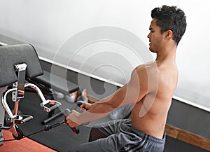 Fitness, rowing machine and shirtless man in gym for health, wellness or bodybuilding workout. Exercise, strong and