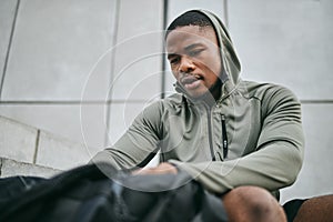 Fitness, runner and sports bag with a black man athlete taking a break from his exercise in the city. Workout, training