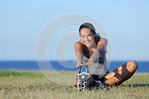 Fitness runner woman stretching on the grass