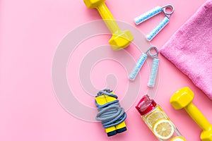 Fitness set with bars, towel, bottle of water and wrist builder on pink background top view mock up