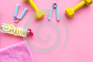 Fitness set with bars, towel, bottle of water and wrist builder on pink background top view mock up