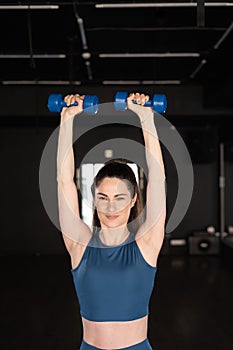 fitness, sport, bodybuilding and weightlifting concept. close up of young latina woman with dumbbells flexing muscles in