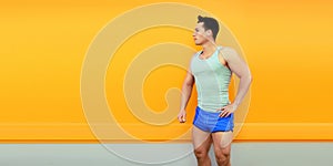 Fitness, sport concept - sportsman posing listening to music in earphones looking away on orange background, blank copy space