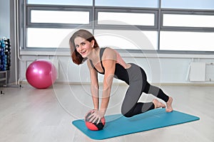 Fitness, sport, exercising lifestyle - fit woman doing exercise on mat with medicine ball at gym