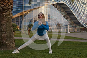 Fitness sport girl in sportswear doing fitness exercise in the street,outdoor sports. Sports girl in light clothing is