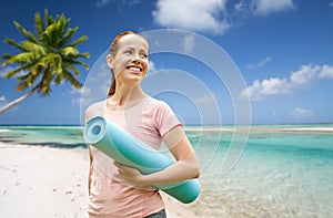 Happy smiling woman with exercise mat over beach
