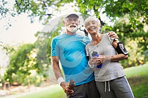 Fitness, sport and lifestyle concept - happy mature couple in sports clothes outdoors