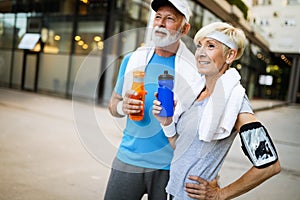 Fitness, sport and lifestyle concept - happy mature couple in sports clothes outdoors