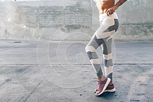 Fitness sport model in fashion sportswear posing over gray wall