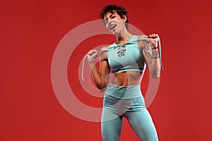 Fitness and sport motivation.. Strong and fit athletic, woman with tattoo posing on red background in sportswear.