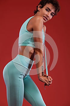 Fitness and sport motivation.. Strong and fit athletic, woman with tattoo posing on red background in sportswear.