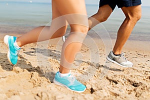 Legs of sportsmen in sneakers running along beach