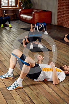 fitness, sport, training, gym and lifestyle concept - group of people working out with rubber bands in the gym.