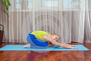 Fitness. sport, training and lifestyle concept - Child doing exercises on mat in home.