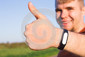 Fitness, sport, training and lifestyle concept - close up of young man with heart-rate watch bracelet in summer park.