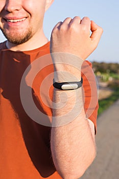 Fitness, sport, training and lifestyle concept - close up of young man with heart-rate watch bracelet in summer park.