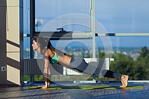 Fitness, sport, training and lifestyle concept - smiling woman stretching on mat in gym. light from a large window.