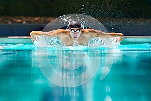 Fitness, sport and training with man in swimming pool for competition, workout and energy. Strong, water splash and