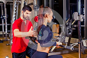 Fitness, sport, training and people concept - Personal trainer helping woman working with in gym