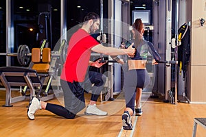 Fitness, sport, training and people concept - Personal trainer helping woman working with in gym