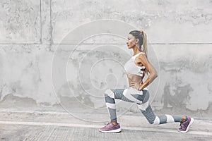 Fitness sport woman in fashion sportswear doing workout over gray wall