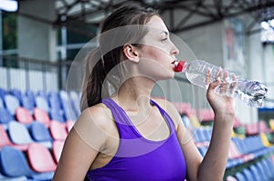 Fitness sport woman in fashion sportswear, the girl is drinking water, fitness exercise in the city street