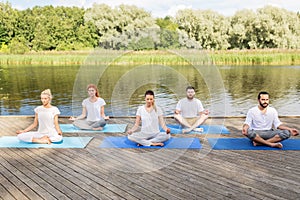 People meditating in yoga lotus pose outdoors photo