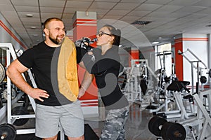 Fitness, sports, exercises and weightlifting. Concept - a young woman and a young man with dumbbells sweeping muscles in