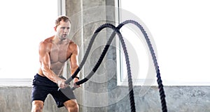 Fitness and sports man training with battle rope in cross fit gym. Fitness Healthy lifestye and workout at gym concept photo