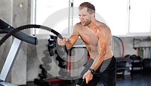 Fitness and sports man training with battle rope in cross fit gym. Fitness Healthy lifestye and workout at gym concept photo