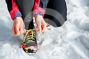Fitness, sports, people, and lifestyle concept - close up of a young sporty woman tying shoelaces outdoors in winter