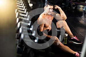 Fitness and sportsman taking a break after training lifting dumbbell sitting at the gym . Fitness Healthy lifestye and workout at photo