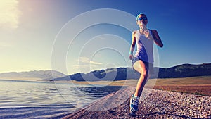 Fitness sporty woman running on rocky seaside