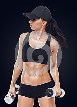 Fitness sporty woman in training pumping up muscles with dumbbells