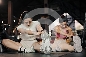 Fitness, stretching and two woman at gym for a warm up workout, training and body wellness with exercise. Young sports female or