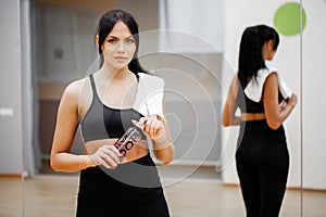 Fitness time. Beautiful young woman resting and drinking water in the gym