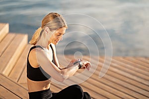 Fitness Tracker. Sporty Middle Aged Woman Looking At Smartwatch While Training Outdoors